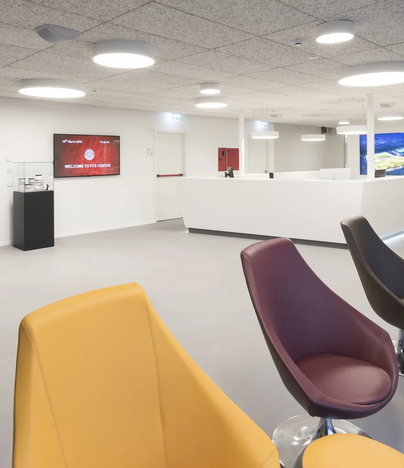 Moderne Empfangshalle mit farbigen Stühlen und Vitrinen mit Pokalen