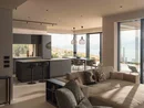 INTERIOS. Il tuo studio di interior design. Soggiorno moderno con cucina, divano e finestre panoramiche affacciate sul paesaggio e sul mare