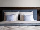 Gemachtes Bett mit blauen und weißen Kissen vor einem Holzpaneel