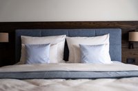 Gemachtes Bett mit blauen und weißen Kissen vor einem Holzpaneel