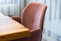 Nahaufnahme eines gepolsterten Stuhls neben einem Holztisch