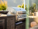 Moderner Gasgrill im Außenbereich mit Pfanne und Kochutensilien bei Sonnenschein