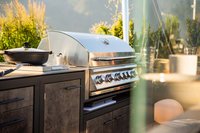 Moderner Gasgrill im Außenbereich mit Pfanne und Kochutensilien bei Sonnenschein