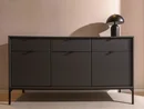 INTERIOS. Il tuo studio di interior design. Credenza nera con frontale scanalato e lampada da tavolo davanti a una parete rosa