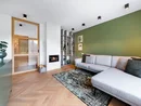 Modernes Wohnzimmer mit grauem Sofa, grünem Akzentwand und kleinem Kamin