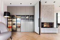 Moderner Wohnraum mit grauem Schrank, beleuchteten Vitrinen und Kamin