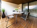 Moderner Balkon mit Tisch, vier Stühlen, Pflanze und Bergblick