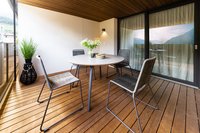 Moderner Balkon mit Tisch, vier Stühlen, Pflanze und Bergblick