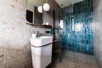 Moderner Badbereich mit weißem Waschbecken und blauen Fliesen in der Dusche