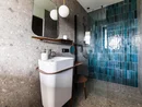 Moderner Badbereich mit weißem Waschbecken und blauen Fliesen in der Dusche
