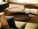 Drei runde Tische unterschiedlicher Höhe auf einem Teppich neben einem Sofa