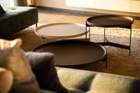 Drei runde Tische unterschiedlicher Höhe auf einem Teppich neben einem Sofa