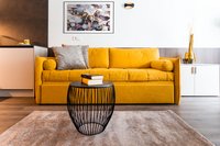 Gelbes Sofa mit Kissen und Büchern auf schwarzen Drahttisch im Wohnzimmer