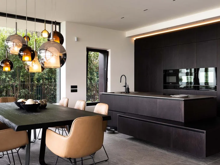 Zona pranzo moderna con sedie marroni e cucina in legno scuro