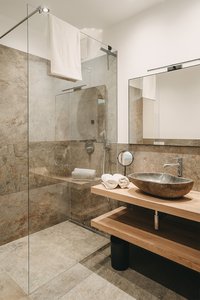 Moderner Badezimmerbereich mit Glasdusche und Natursteinwaschbecken