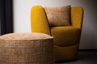 Gelber Sessel mit passendem Hocker und Kissen in modernem Raum