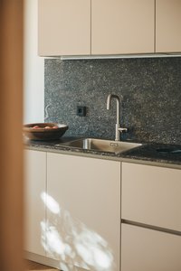 Moderne Küchenspüle mit grauer Arbeitsplatte und Obstschale aus Holz