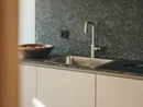 Lavandino moderno in cucina con piano di lavoro grigio e ciotola di frutta in legno