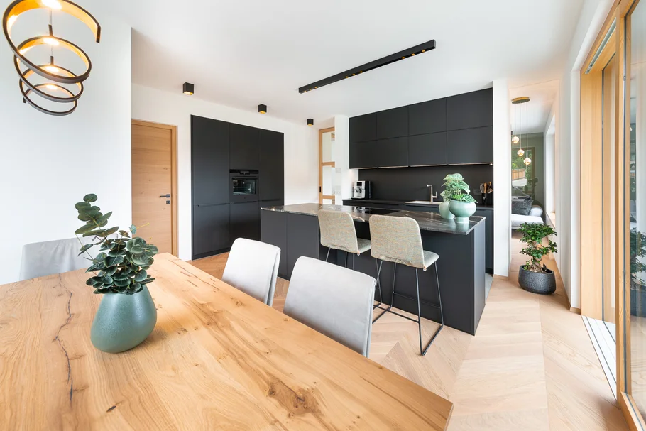 Moderne schwarze Küche mit Holz-Esstisch und großer Fensterfront