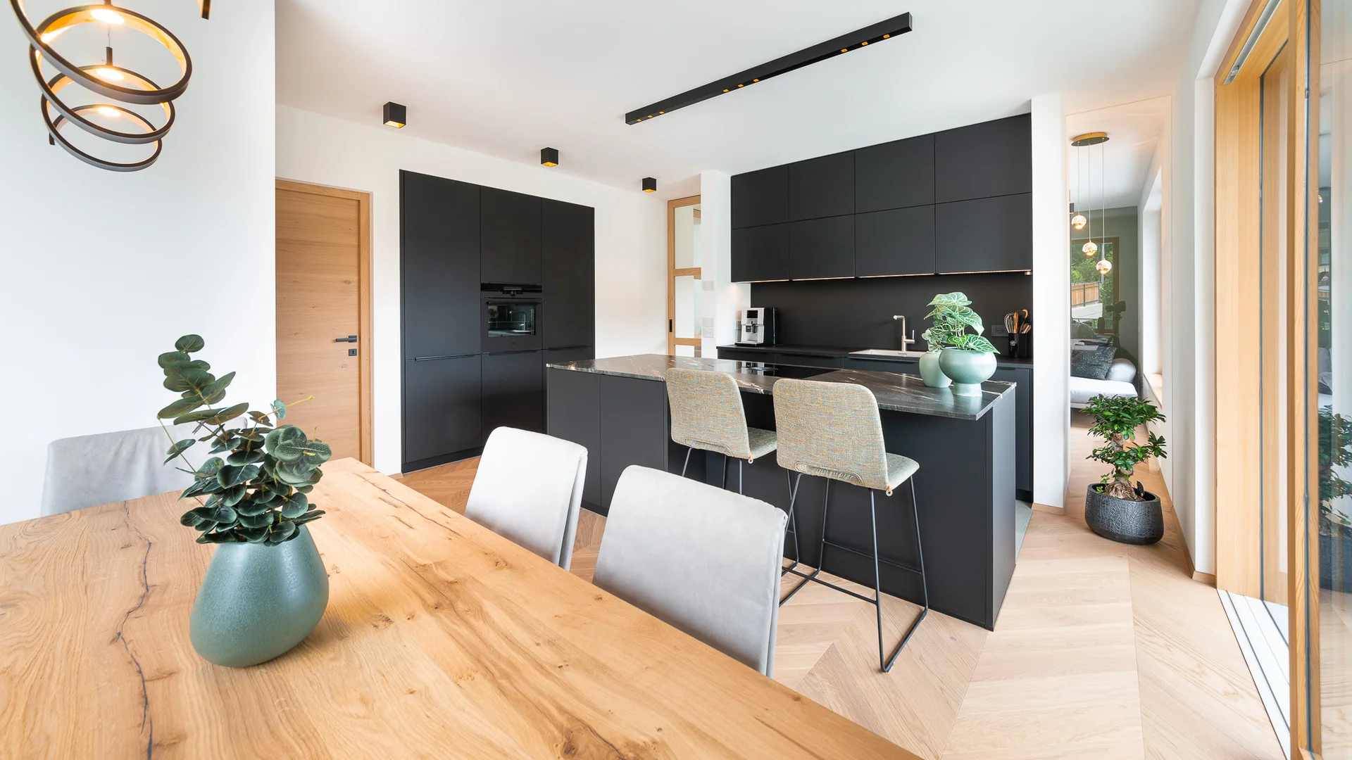 Moderne schwarze Küche mit Holz-Esstisch und großer Fensterfront