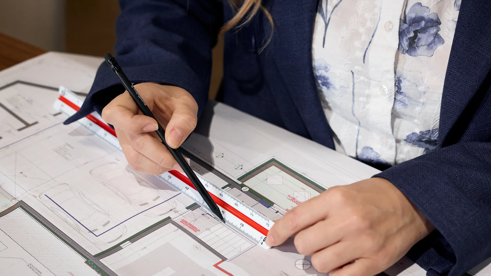 Person misst Architekturplan mit Lineal und Stift