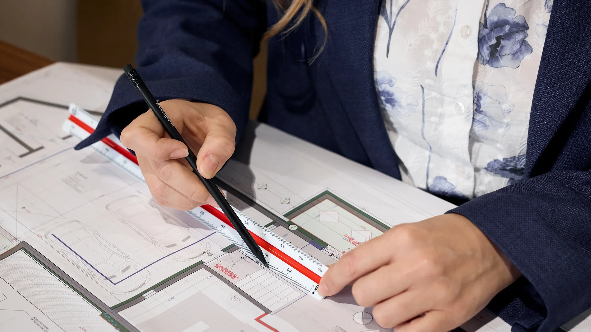 Person misst Architekturplan mit Lineal und Stift