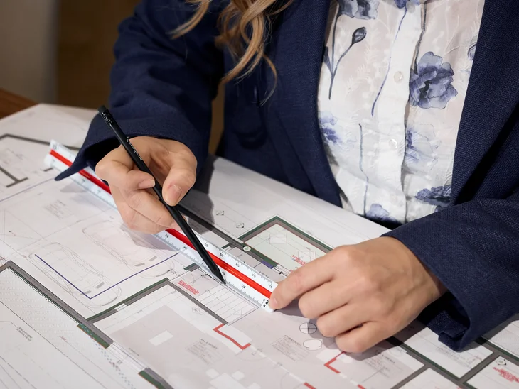Person misst Architekturplan mit Lineal und Stift
