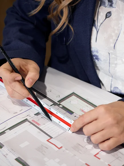 Person misst Architekturplan mit Lineal und Stift