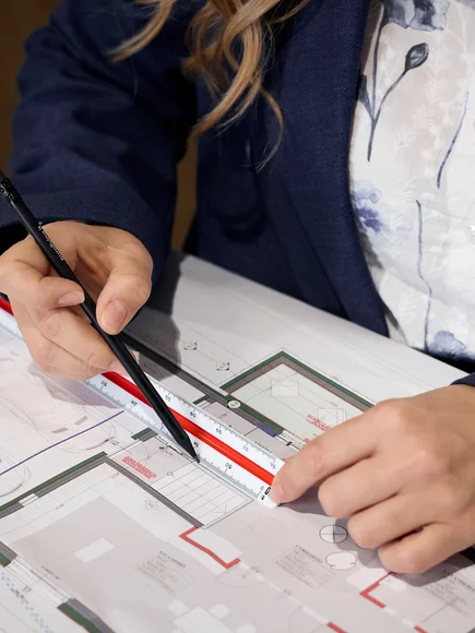 Person misst Architekturplan mit Lineal und Stift