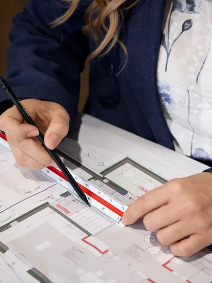 Person misst Architekturplan mit Lineal und Stift