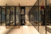 Begehbarer Kleiderschrank mit Glasfronten, Kleidung und Sitzbank
