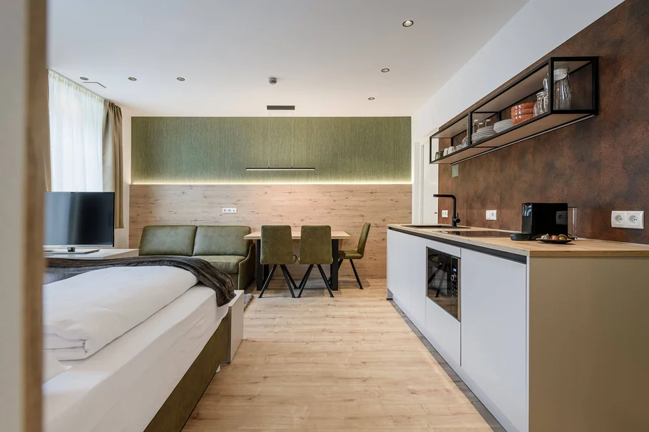 Moderner Wohnbereich mit Küche, Essplatz und Sofa in neutralen Farben