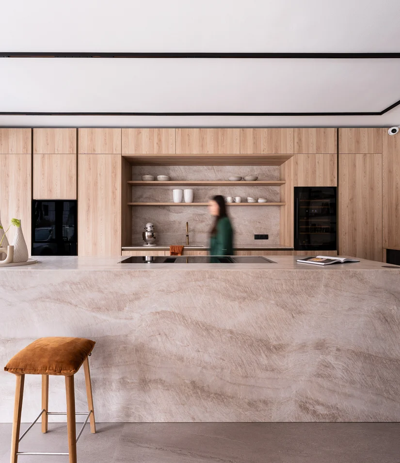 Moderne Küche mit Holzschränken, Marmorinsel und braunem Hocker