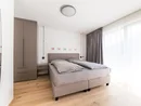 Modernes Schlafzimmer mit Doppelbett, grauer Gardine und Holzfußboden