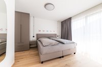Modernes Schlafzimmer mit Doppelbett, grauer Gardine und Holzfußboden