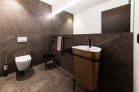 Moderne Toilette und Waschbecken in braunem Badezimmer mit großem Spiegel