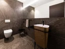 Moderne Toilette und Waschbecken in braunem Badezimmer mit großem Spiegel