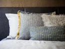 Mehrere dekorative Kissen unterschiedlicher Muster und Texturen auf einem Bett