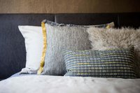 Mehrere dekorative Kissen unterschiedlicher Muster und Texturen auf einem Bett