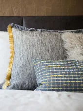 Mehrere dekorative Kissen unterschiedlicher Muster und Texturen auf einem Bett