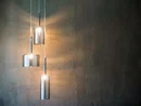 Drei moderne hängende Glaskolbenlampen an einer dunklen Wand