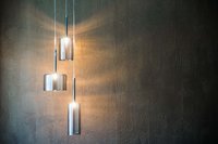 Drei moderne hängende Glaskolbenlampen an einer dunklen Wand