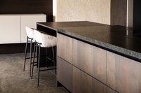 Moderne Kücheninsel mit Holzfronten und zwei gepolsterten Barhockern