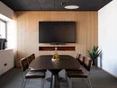 Moderner Besprechungsraum mit Fernseher, Holzwand und sechs Stühlen