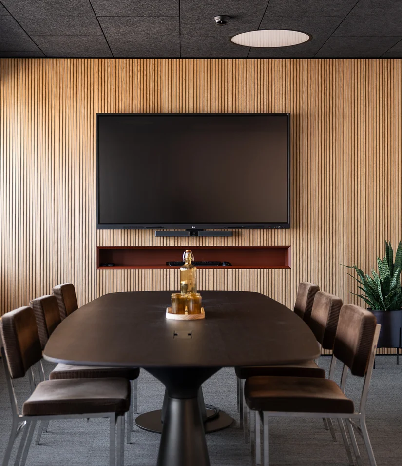 Moderner Besprechungsraum mit Fernseher, Holzwand und sechs Stühlen