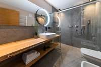 Modernes Badezimmer mit Holzablage, beleuchtetem Spiegel und Glasdusche