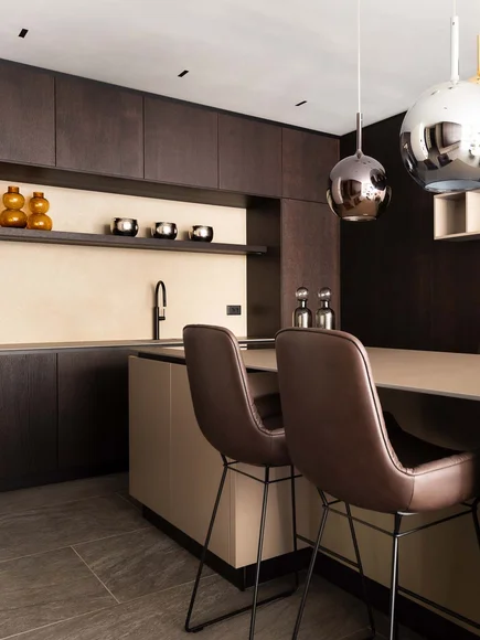 Moderne Küche mit dunklen Holzschränken und zwei braunen Barhockern