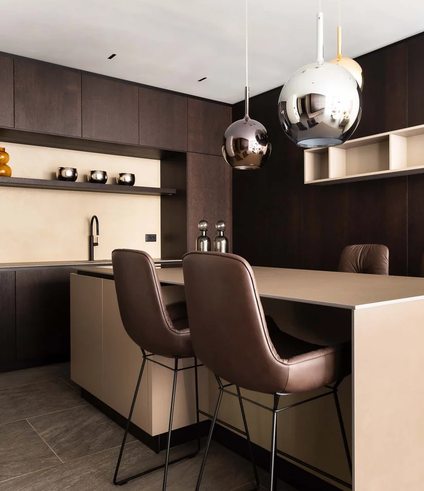 Moderne Küche mit dunklen Holzschränken und zwei braunen Barhockern