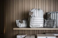 Gestreifte Taschen mit Herzanhängern auf einem Holzregal vor Holzwand