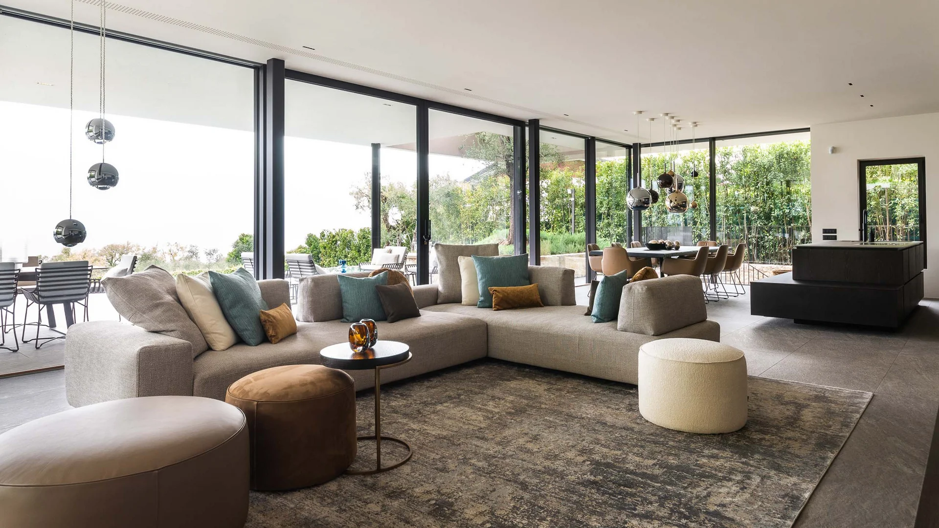 Moderner Wohnbereich mit Ecksofa, Sitzhockern und großen Glasfenstern